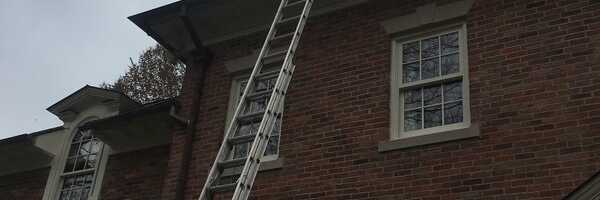 Ladder set against a brick home for gutter cleaning